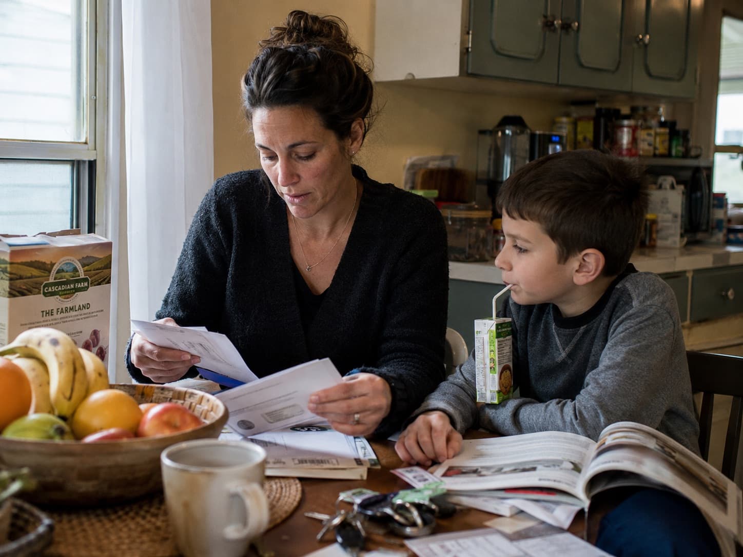 A mother and her son going through paperwork at the kitchen table